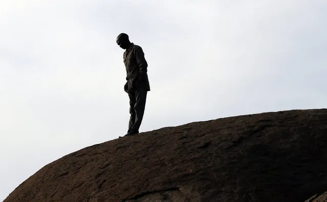 A mine worker stands on a hill waiting for the commemoration to get under way in Marikana in Rustenburg, South Africa, Tuesday, August 16, 2016. On Aug. 16, 2012 police shot and killed 34 striking Lonmin miners, apparently while trying to disperse them and end their strike. Ten people, including two police officers and two Lonmin security guards, were killed in the preceding week. (Photo by Themba Hadebe/AP Photo)
