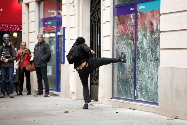 A demonstrator destroys a bank window during clashes at a demonstration in Paris as part of a nationwide day of strike and protests for higher wages and against requisitions at refineries in France on October 18, 2022. (Photo by Benoit Tessier/Reuters)