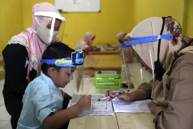 Teachers and students wear protective gear as a precaution against the new coronavirus outbreak during a class at a Quran educational facility at on the outskirts of Jakarta, Indonesia, Wednesday, July 1, 2020. The government of Indonesia's capital region is extending the first transition phase from large-scale social restrictions in Jakarta as the number of new confirmed coronavirus cases continues to rise. (Photo by Tatan Syuflana/AP Photo)
