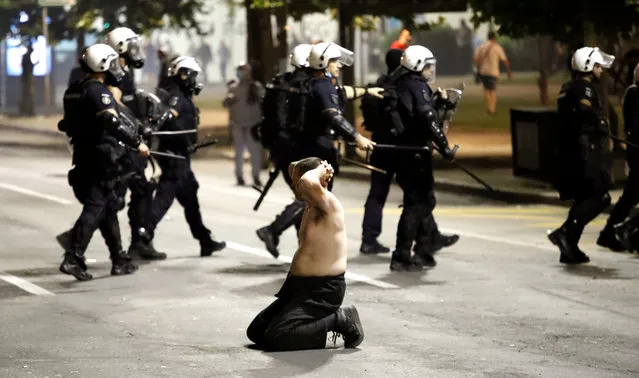 A man kneels during clashes with police outside the Serbian Parliament building in Belgrade, Serbia, 07 July 2020 (issued 08 July 2020). Hundreds gathered to protest after President Aleksandar Vucic announced that a weekend curfew would be enforced amid a surge in coronavirus cases. (Photo by Koca Sulejmanovic/EPA/EFE)