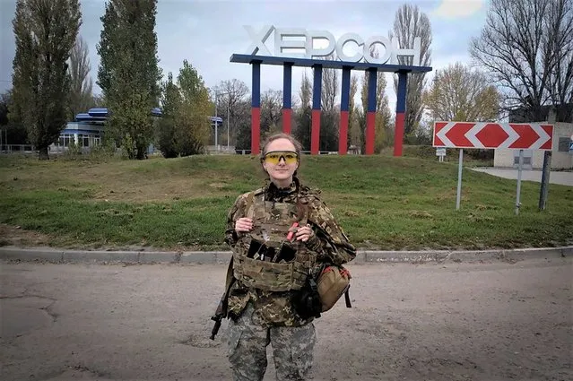 A Ukrainian female soldier poses for a photo against a Kherson sign in the background, in Kherson, Ukraine, Friday, November 11, 2022. (Photo by Dagaz/AP Photo)