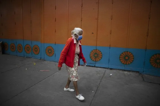 An elderly woman wearing a protective face mask walks on a street in Caracas, Venezuela, Friday, July 17, 2020, amid the new coronavirus pandemic. (Photo by Ariana Cubillos/AP Photo)