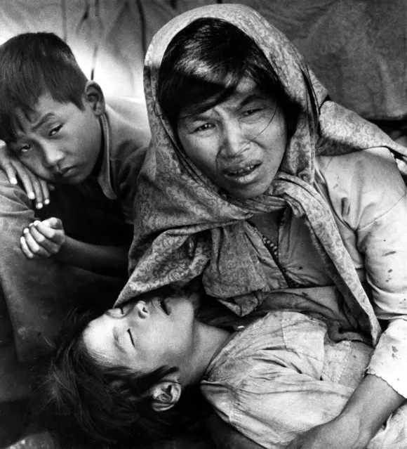 A Vietnamese mother, Mrs. Nguyen Thi Yen, holds her sick child as she pleads help from a fishing boat carrying her and 48 other refugees as they arrive at Khlong Yai, a village 220 miles southeast of Bankgkok, Thailand, November 30, 1977. The refugees were refused entry and the boat was towed back to sea. (Photo by Eddie Adams/AP Photo)