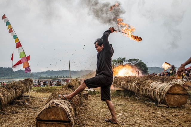 A participant ignites a tree-trunk cannon to create an explosive sound using carbide and water during the Kuluwung Festival, a two-day traditional sound battle held annually between two villages on opposite sides of a river in Sukasirna, West Java, on April 5, 2025. (Photo by Aditya Aji/AFP Photo)