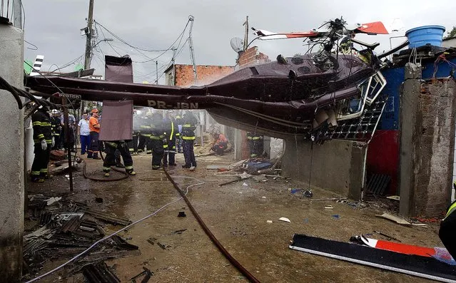 Firefighters work at the site where a helicopter crashed into a residential area of Sao Paulo, Brazil, January 21, 2013. According to authorities, the pilot flying the private helicopter died, and three passengers were injured. Sao Paulo has one of the world's largest private fleets of helicopters, used as a means of bypassing extremely congested roads. (Photo by Andre Penner/Associated Press)