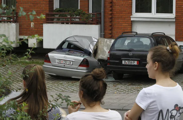 Girls look at a car, demolished by a concrete block after an earthquake in Skopje, Macedonia, Sunday, September 11, 2016. Macedonian authorities say an earthquake with a preliminary magnitude of 5.3 struck on the outskirts of the capital, Skopje, Sunday causing minor damage to buildings but no injury. (Photo by Boris Grdanoski/AP Photo)