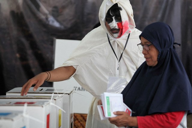 An electoral worker at a hantu (ghost) themed general election polling booth, assists a voter with her ballot in Surabaya, East Java, Indonesia on February 14, 2024. The electoral workers donned the costumes as a creative effort to increase voter participation. (Photo by Didik Suhartono/Antara Foto via Reuters)