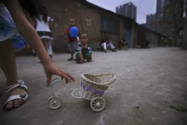 A Chinese girl, reaches for her toy, while playing outside her house along with other children, in a Hutong, or a traditional alleyway of Beijing, China, Sunday, June 13, 2010. (Photo by Muhammed Muheisen/AP Photo)