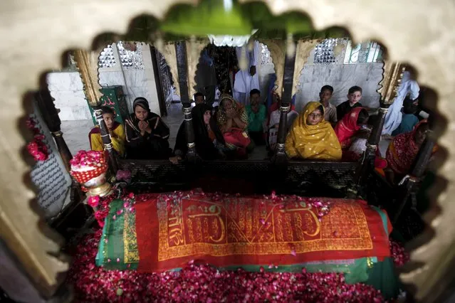 Devotees pray at the grave while visiting the shrine of Hasan-al-Maroof Sultan Manghopir, better known as the crocodile shrine, on the outskirts of Karachi, Pakistan October 11, 2015. (Photo by Akhtar Soomro/Reuters)