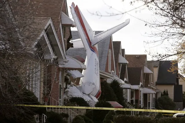 A small cargo plane is seen crashed into the side of a home in Chicago, November 18, 2014. The occupants of the home escaped uninjured after the crash at 2:42 a.m. CST but Chicago police said they did not have information about potential injuries sustained by the pilot, who authorities said was the only occupant of the plane. (Photo by Andrew Nelles/Reuters)