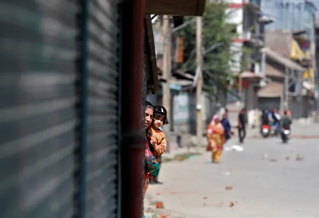 A Kashmiri woman holds a girl as they watch a protest after a gun battle between suspected militants and Indian security forces in Srinagar on September 17, 2020. (Photo by Danish Ismail/Reuters)