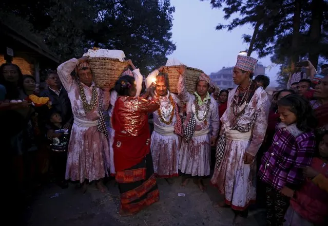 Priests covered in bloodstains carry offerings as they perform rituals to mark the "Dashain", Hinduism's biggest religious festival in Bhaktapur, Nepal October 22, 2015. Hindus in Nepal celebrate victory over evil during the festival by flying kites, feasting, playing swings, sacrificing animals and worshipping the Goddess Durga as well as other gods and goddess as part of celebrations held throughout the country. (Photo by Navesh Chitrakar/Reuters)