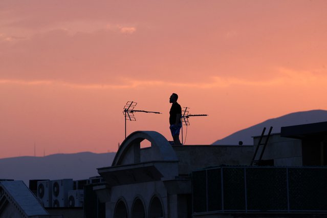 A man stands on the roof of a building while watching the horizon in Tehran on June 16, 2025. Iran's state broadcaster was briefly knocked off the air by an Israeli strike and explosions rang out across Tehran on June 16, after a barrage of Iranian missiles killed 11 people in Israel on the fourth day of an escalating air war. (Photo by Atta Kenare/AFP Photo)