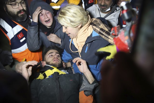 Rescuers and mother surround Adnan Mohammet Korkut after he was rescued in Gaziantep, southern Turkey, early Friday, February 10, 2023. The teenager was pulled largely unscathed from beneath the rubble of a collapsed building in the Turkish city of Gaziantep early Friday, in a dramatic rescue that belied the reality that the chances of finding many more survivors four days after a catastrophic earthquake killed tens of thousands are shrinking fast. (Photo by IHA via AP Photo)