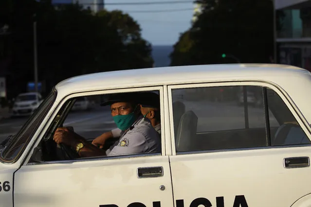 Police officers wearing masks as a precaution against the spread of the new coronavirus drive a patrol car on an empty street during curfew in Havana, Cuba, Tuesday, September 1, 2020. Cuban authorities launched a strict 15-day lockdown of Havana in order to stamp out the low-level but persistent spread of the novel coronavirus in the capital. (Photo by Ramon Espinosa/AP Photo)