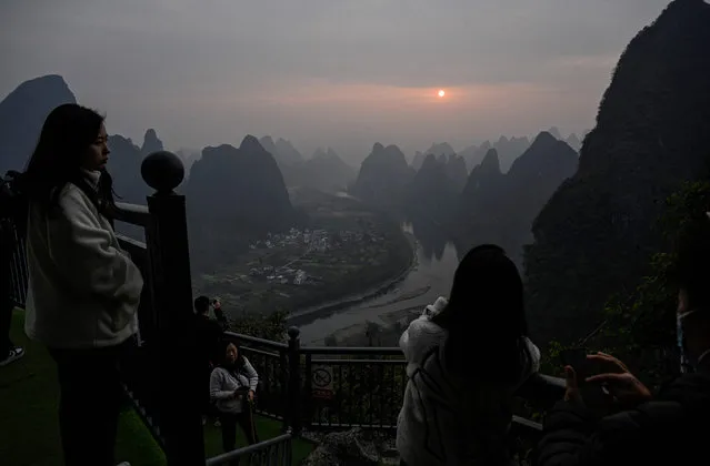 Tourists watch the sunrise at a scenic tourist spot on Xianggong Mountain, on the west bank of Li River in Yangshuo city, in southern China's Guangxi province on February 21, 2023. (Photo by Jade Gao/AFP Photo)