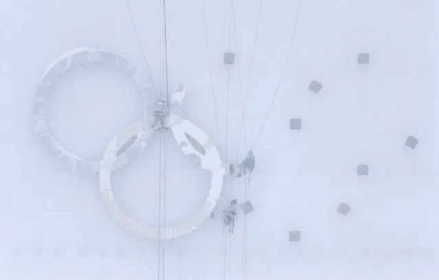 People work on the Olympic rings during heavy snow at the Laura Cross-country Ski and Biathlon Centre in Krasnaya Polyana near Sochi, in this January 24, 2014 file photo. (Photo by Alexander Demianchuk/Reuters)