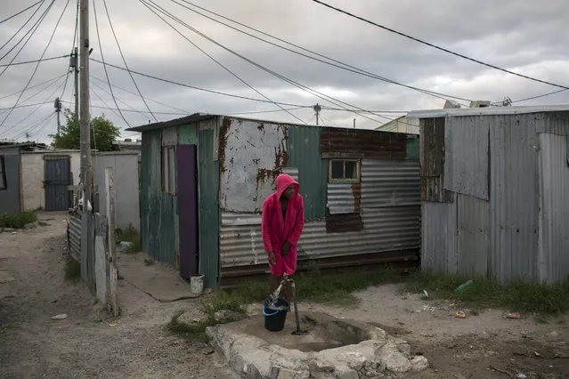 A woman collects water in a settlement near Cape Town on Friday, February 2, 2018. South Africa's drought-hit city of Cape Town introduced new water restrictions in an attempt to avoid what it calls “Day Zero”, the day in mid-April when it might have to turn off most taps. (Photo by Bram Janssen/AP Photo)