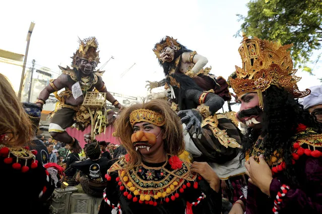 Dancers stand in front of a giant “ogoh-ogoh” effigies or bewilder evil spirits during a parade to celebrate “Nyepi” or Bali's Day of Silence which falls on Hindu New Year in Denpasar, Bali, Indonesia, Tuesday, March 21, 2023. Most Balinese keep self-reflection and stay at home to observe quiet holiday. Tourists visiting the island, are asked not to leave their hotels and the airport will be closed. (Photo by Firdia Lisnawati/AP Photo)
