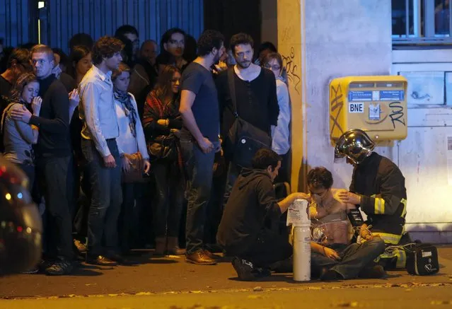 A member of the French fire brigade aids an injured individual near the Bataclan concert hall following fatal shootings in Paris, France, November 13, 2015. (Photo by Christian Hartmann/Reuters)