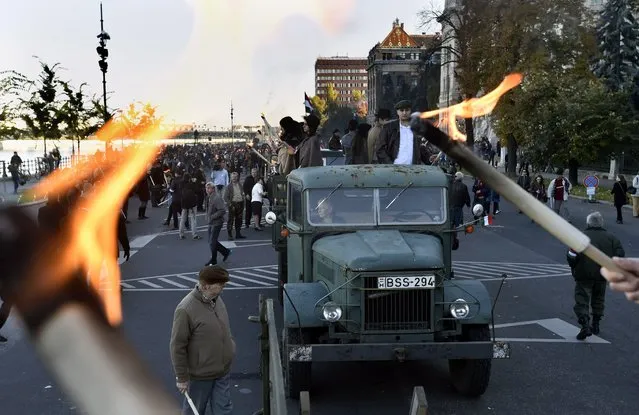An old, historical truck is seen between torchlights as participants prepare for a march from the Budapest University of Technology and Economics through the streets of Budapest to re-enact the protest march of Hungarian students in 1956 which ignited the revolution and war of independence against communist rule and the Soviet Union, Saturday, October 22, 2016, the eve of the 60th anniversary of the outbreak of the 1956 revolution in Hungary. The Hungarian Revolution of 1956 or the Hungarian Uprising of 1956 was a nationwide revolt against the government of the Hungarian People's Republic and its Soviet-imposed policies, lasting from 23 October until 10 November 1956. (Photo by Zoltan Mathe/MTI via AP Photo)