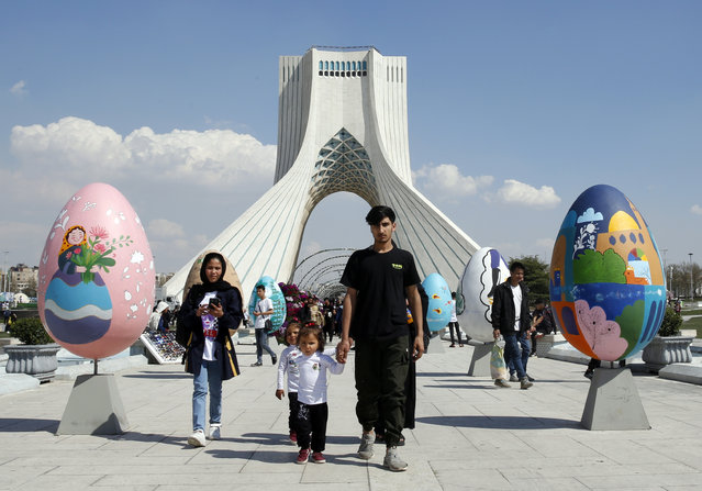 A family walks between colorful decoration in the shape of eggs, a symbol of “Nowruz”, the Persian New Year, displayed around the Azadi (Freedom) square on the eve of Nowruz celebrations in Tehran, Iran, 20 March 2023. Nowruz, which has been celebrated for at least three thousand years, is the most revered celebration in the greater Persian world, which includes the countries of Iran, Afghanistan, Azerbaijan, Turkey, and portions of western China and northern Iraq. (Photo by Abedin Taherkenareh/EPA/EFE)
