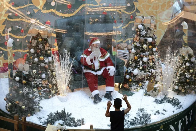 Abilio Nunes, a Santa Claus performer, waves to children from inside a bubble, a protective measure against the spread of COVID-19, at a shopping center in Brasilia, Brazil, Wednesday, December 16, 2020. (Photo by Eraldo Peres/AP Photo)