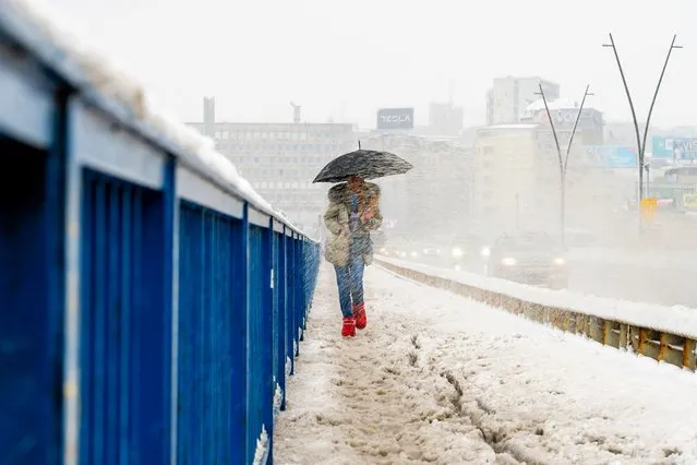A pedestrian walks ona bridge during a heavy snowfall in Belgrade, Serbia on April 4, 2023. (Photo by Andrej Isakovic/AFP Photo)