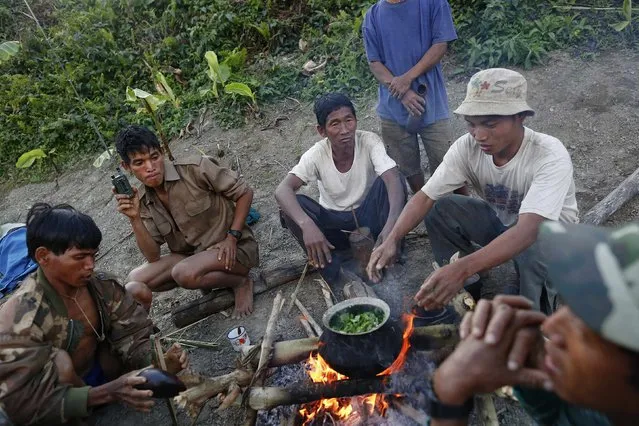 Naga men prepare dinner at a hunting base camp in an opium field during a hunting trip between Donhe and Lahe township in the Naga Self-Administered Zone in northwest Myanmar December 26, 2014. The traditional dish includes leaves from opium poppies as well as mustard, which the Naga plant in poppy fields because they say that gives it a better flavour. (Photo by Soe Zeya Tun/Reuters)