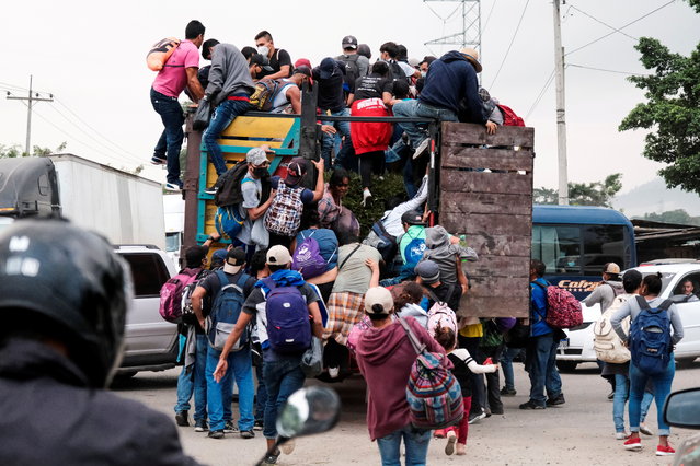 Hondurans climb onto the back of a truck for a ride in a new caravan of migrants, set to head to the United States, in Cofradia, Honduras on January 15, 2021. (Photo by Yoseph Amaya/Reuters)