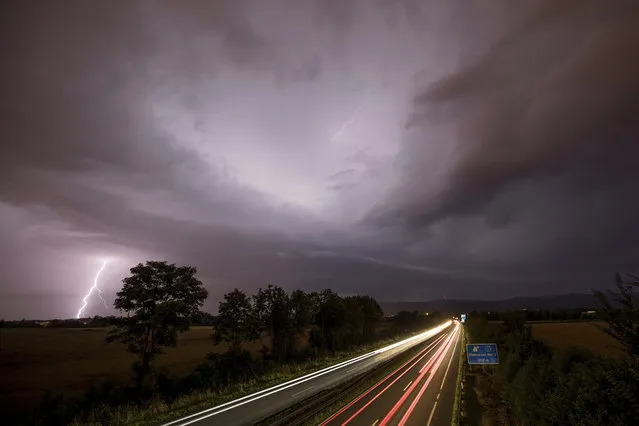 In this photo made with a long exposure, cars drive by as lightning strikes during thunderstorms in Oberursel, Germany, near Frankfurt on Saturday, July 22, 2017. (Photo by Jan Eifert/DPA via AP Photo)