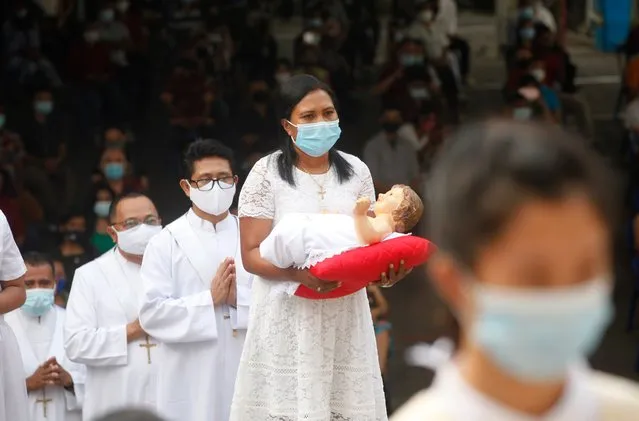A woman wearing face mask carries a baby Jesus statue during a procession for a Christmas mass service at a church in Bali, Indonesia, Thursday, December 24, 2020. (Photo by Firdia Lisnawati/AP Photo)