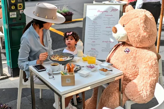 Customers sit with a teddy bear used to keep social distancing measures, during the gradual reopening of commercial activities amid the novel coronavirus pandemic, at a restaurant in Polanco neighborhood, in Mexico City, on July 26, 2020. (Photo by Pedro Pardo/AFP Photo)