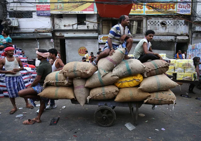 Labourers rest on a handcart loaded with spices in a market area in the old quarters of Delhi, India, June 6, 2018. (Photo by Amit Dave/Reuters)