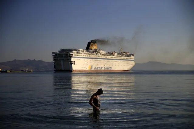 A migrant washes as the passenger ship “Eleftherios Venizelos” leaves the port on the Greek island of Kos, August 19, 2015. (Photo by Alkis Konstantinidis/Reuters)