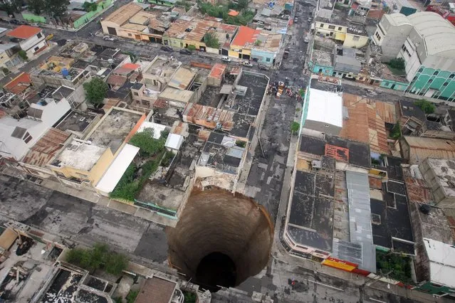 A giant sinkhole in Guatemala City, on May 31, 2010. More than 94,000 were evacuated as the storm buried homes under mud, swept away a highway bridge near Guatemala City and opened up several sinkholes in the capital. (Photo by Casa Presidencial/Reuters via The Atlantic)