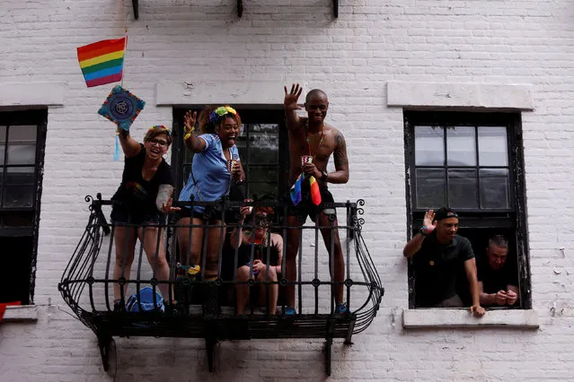 People stand on a fire escape as they watch the 2018 New York City Pride Parade in Manhattan, New York, U.S., June 24, 2018. (Photo by Andrew Kelly/Reuters)