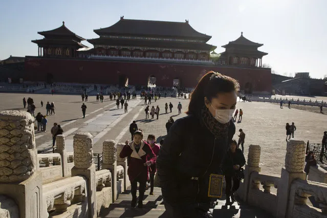 A woman wears a mask as she visits the Forbidden City during a sunny day in Beijing Friday, December 18, 2015. Residents in the Chinese capital are preparing for its second smog red alert as a wave of smog is forecasted to settle over the city from Saturday to Tuesday. (Photo by Ng Han Guan/AP Photo)