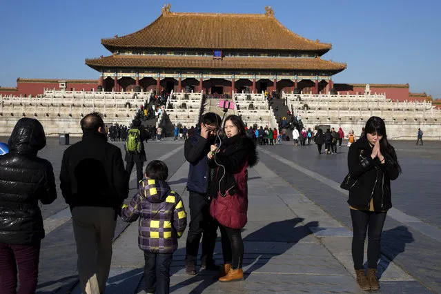A woman clasps her hands together in a prayer at the Forbidden City during a sunny day in Beijing Friday, December 18, 2015. Residents in the Chinese capital are preparing for its second smog red alert as a wave of smog is forecasted to settle over the city from Saturday to Tuesday. (Photo by Ng Han Guan/AP Photo)