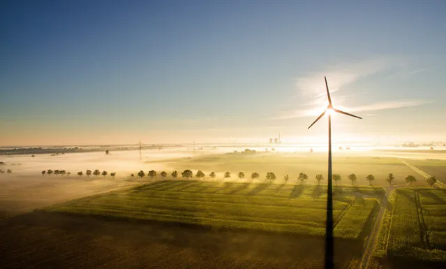 A picture taken with an aerial drone shows fog cloudes in the light of the rising sun over fields with a wind mill in Sehnde in Hanover Region, Germany, 17 August 2016. (Photo by Julian Stratenschulte/EPA)
