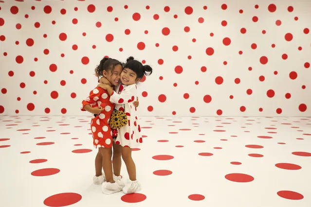 Wearing matching dresses, Takara Thomas, 3, left, and Noemi Vega, 4, hug in a polka-dotted room created by Japanese artist Yayoi Kusama, part of the installation called “With All My Love for the Tulips, I Pray Forever” at the Marciano Art Foundation Friday, August 3, 2018, in Los Angeles. The exhibition is scheduled to run through the spring of 2019. (Photo by Jae C. Hong/AP Photo)