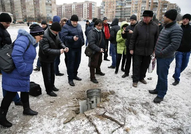 People look at the remains of a rocket shell on a street in the town of Kramatorsk, eastern Ukraine February 10, 2015. Three people were killed and 15 wounded in the rocket strike on the town of Kramatorsk on Tuesday, the government-controlled regional administration said in a statement. (Photo by Gleb Garanich/Reuters)