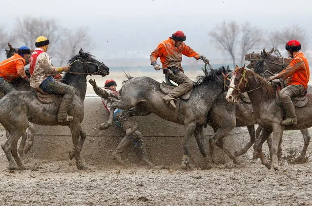 Kyrgyz riders take part in a Kok-Boru regional competition in the village of Sokuluk in Chui Region, Kyrgyzstan March 30, 2021. Kok-Boru is a traditional Central Asian game similar to polo, in which horsemen try to drop the headless carcass of a goat in an opponent's goal. (Photo by Vladimir Pirogov/Reuters)