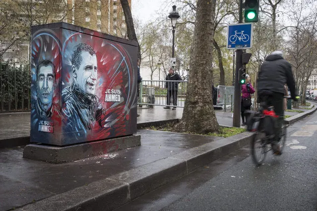 A man rides a bike next to a piece of street art showing the portrait of French policeman Ahmed Merabet, who was killed by the Kouachi brothers as they fled the Charlie Hebdo shooting scene on 07 January 2015, ahead of the first anniversary of the attack, in Paris, France, 05 January 2016. France this week commemorates the victims of last year's Islamist militant attacks on the satirical weekly Charlie Hebdo and a Jewish supermarket with eulogies, memorial plaques and another events. (Photo by Etienne Laurent/EPA)