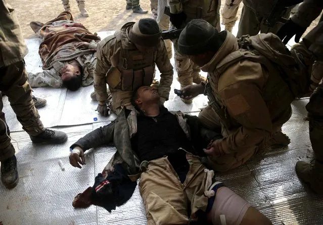 Iraqi injured soldiers, who were wounded during the battle against the Islamic State group, lies on the ground as they receive medical treatment at a field hospital, in Haj Ali frontline village, southern Mosul, Iraq, Tuesday, November 29, 2016. Iraqi forces on Tuesday assaulted villages far south of Mosul in the Nineveh province, attempting to clear rural areas of Islamic State fighters who stayed behind to hinder their advance. (Photo by Hussein Malla/AP Photo)