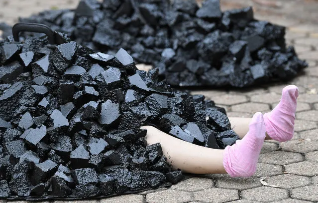 A mannequin depicting a child covered in coal is seen during an Extinction Rebellion Protest in Brisbane, Australia, 22 April 2021. Extinction Rebellion held protest rallies outside the corporate offices of a number of coal companies in the Central Business District of Brisbane. (Photo by Darren England/EPA/EFE)