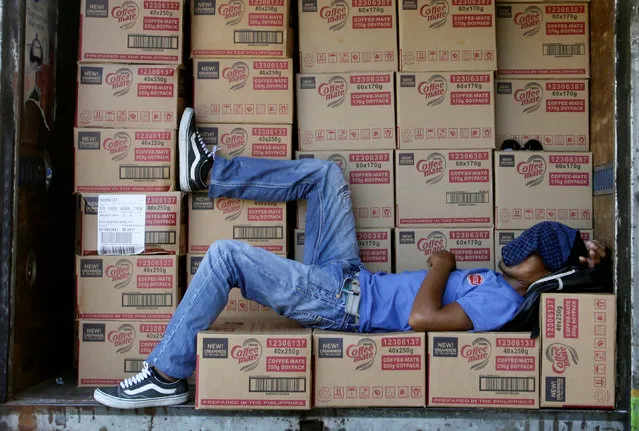 A goods delivery worker rests on boxes containing coffee creamer at the back of his truck in San Fernando, La Union in northern Philippines September 23, 2016. (Photo by Czar Dancel/Reuters)