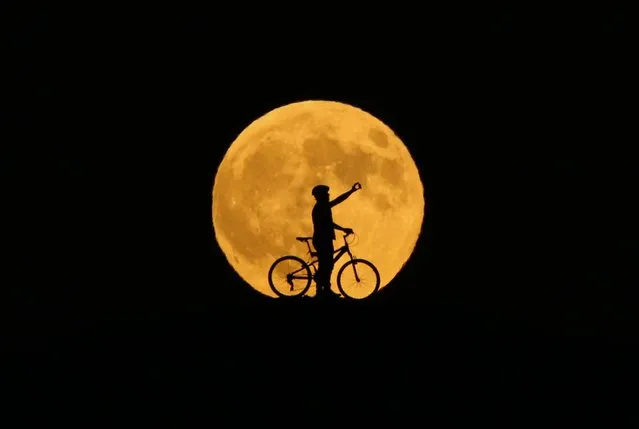 The full moon rises behind silhouette of a man taking a selfie on a bicycle prior to the totally phase of Century's longest “Blood Moon” eclipse in Van, Turkey on July 27, 2018. (Photo by Ozkan Bilgin/Anadolu Agency/Getty Images)