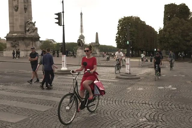A woman rides on the Alexandre III bridge in Paris, Wednesday, September 13, 2023. Years of efforts to turn car-congested Paris into a more bike-friendly city are paying off ahead of the 2024 Olympics, with increasing numbers of people using the French capital's growing network of cycle lanes. (Photo by John Leicester/AP Photo)