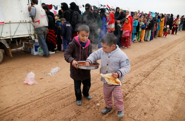 Boys who fled the Islamic State stronghold of Mosul, receive food at a refugee camp, Iraq,December 18, 2016. (Photo by Ammar Awad/Reuters)